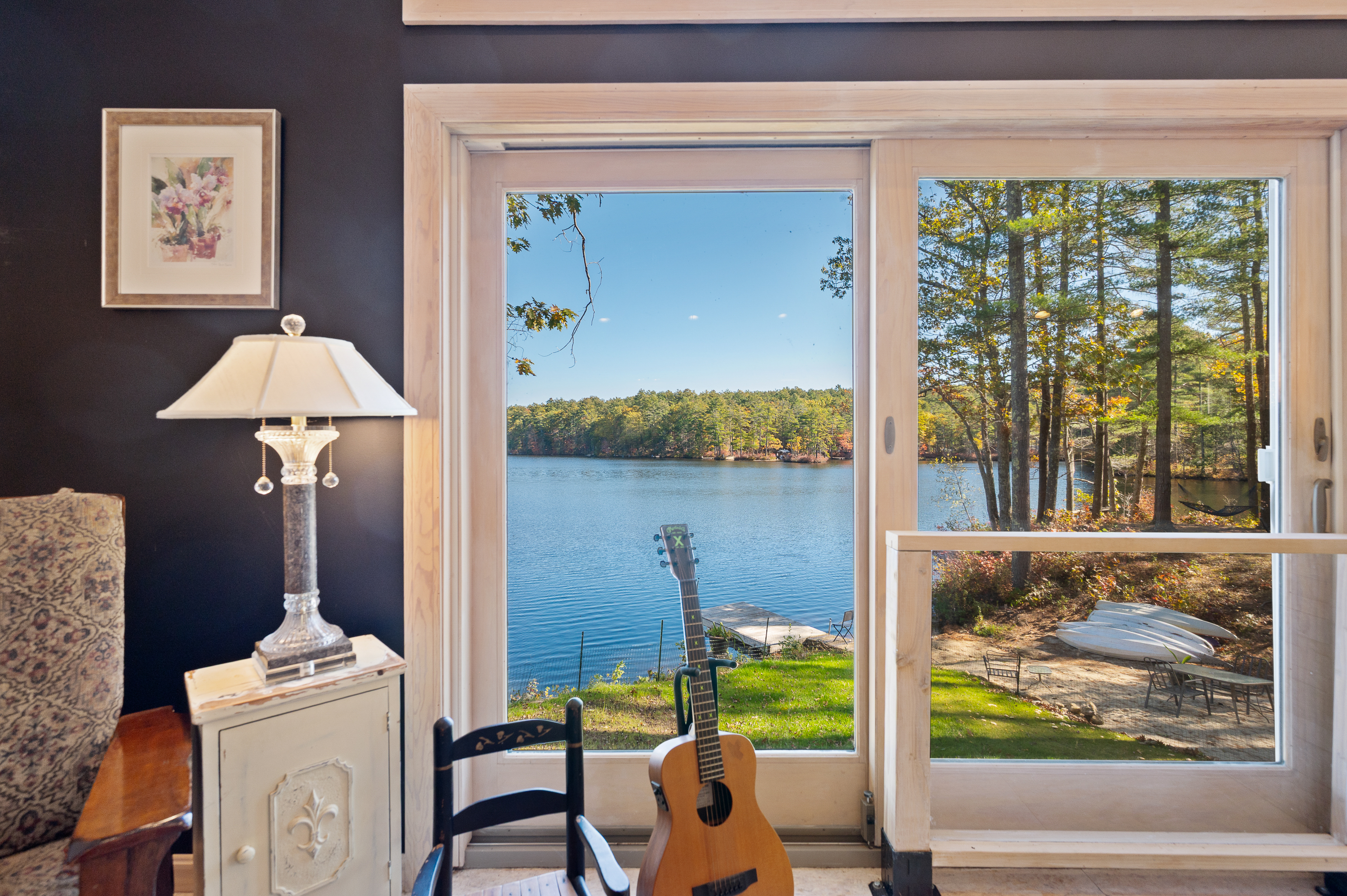 Cozy lakeside view with a guitar and chair by the door.