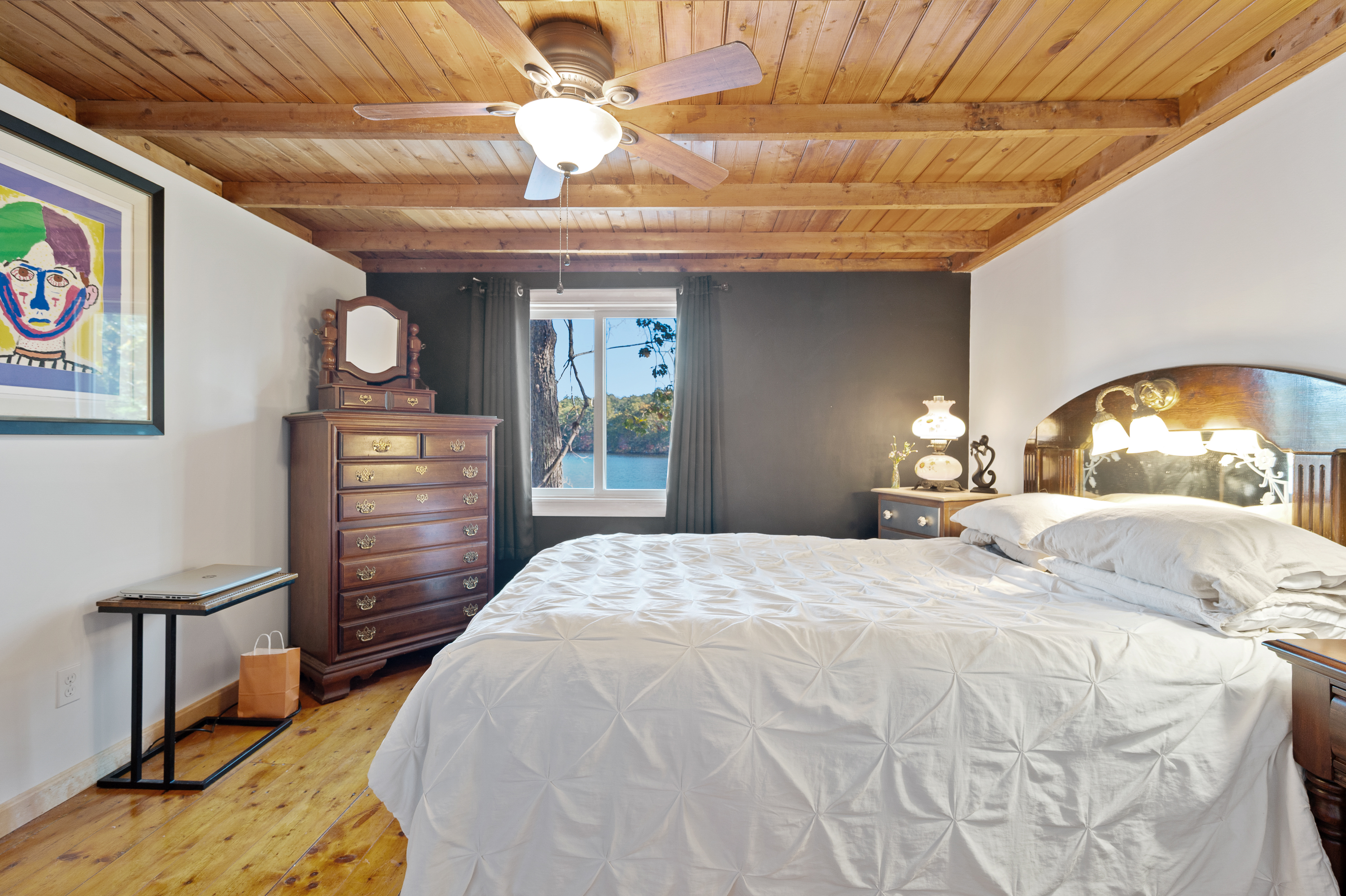Cozy bedroom with wooden ceiling and warm lighting.