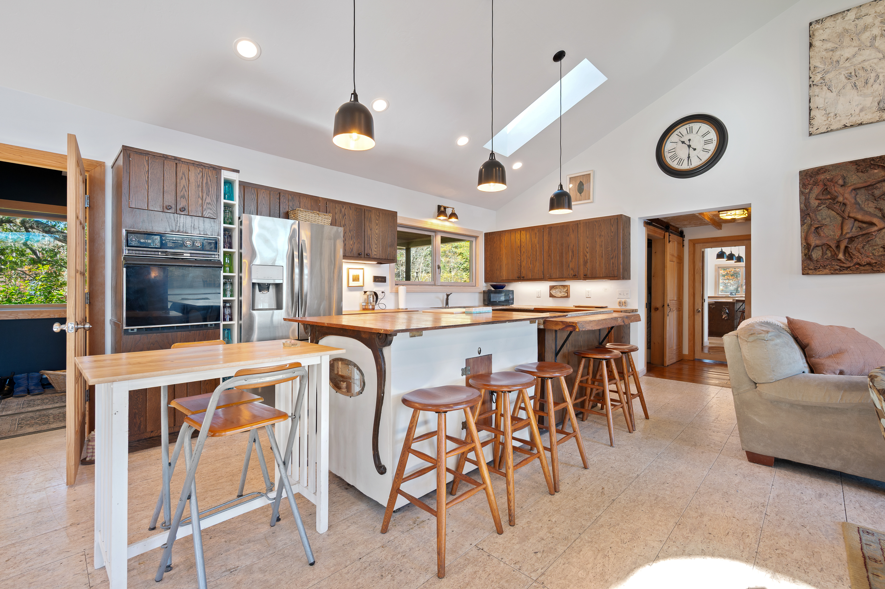Modern kitchen with wooden stools and white countertops.