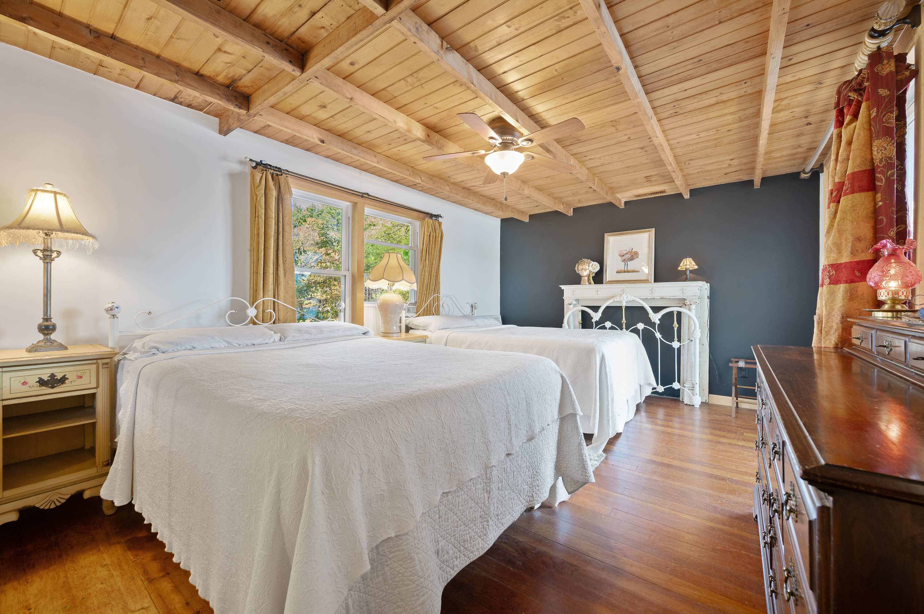 Cozy bedroom with wooden ceiling, twin beds, and a fireplace.