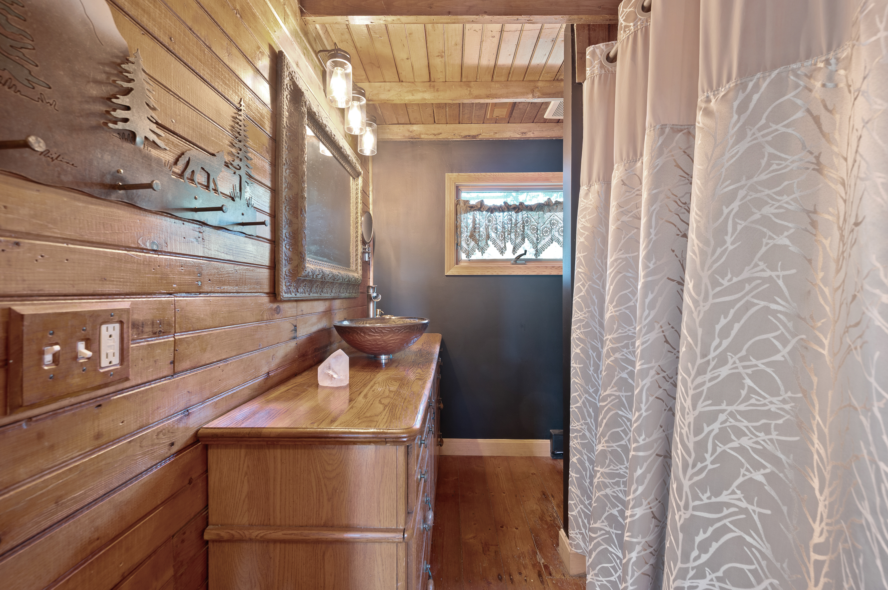 Rustic wooden bathroom with a large mirror and shower curtain.