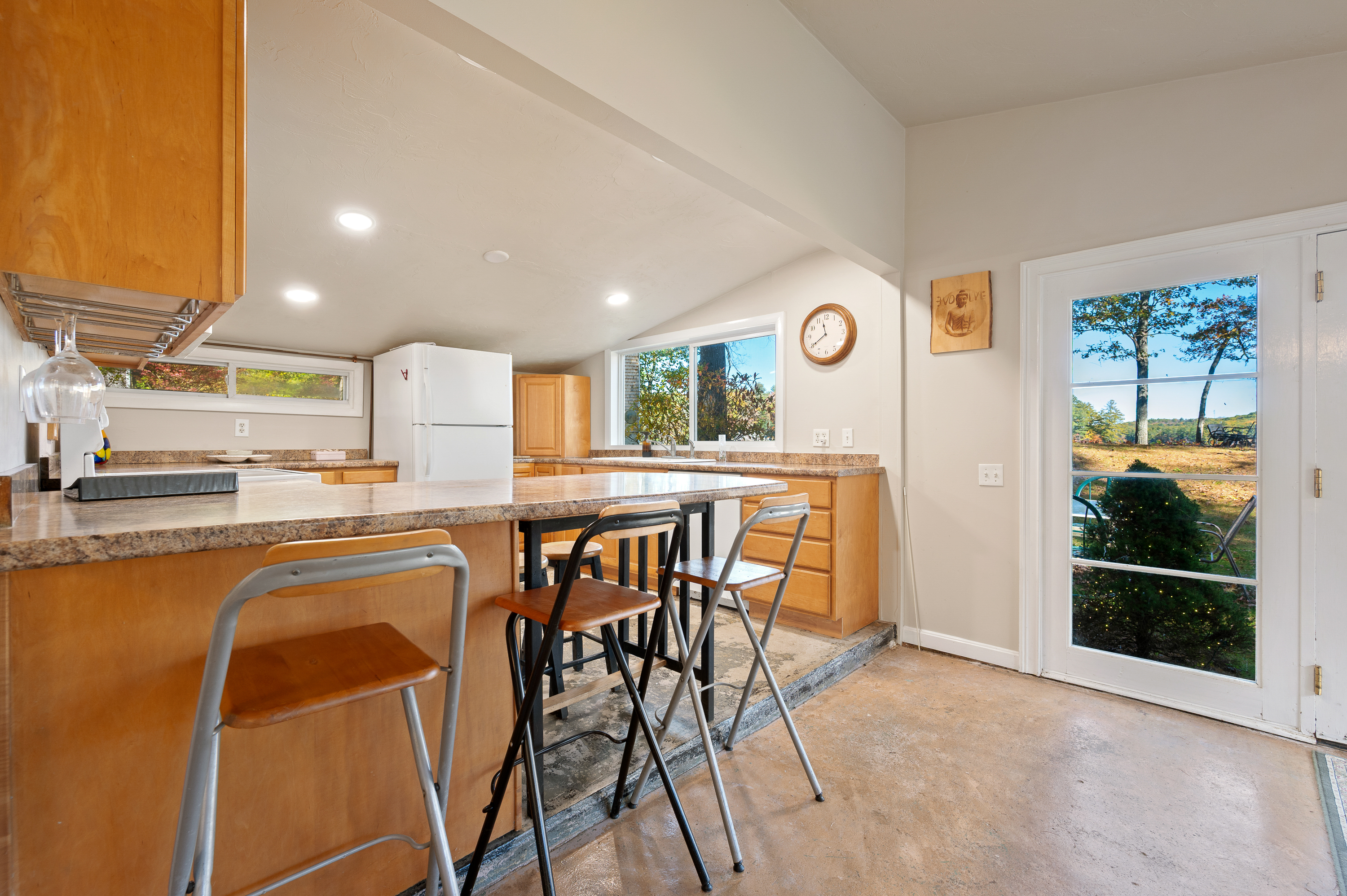 Bright kitchen with wooden cabinets, breakfast bar, and large windows.