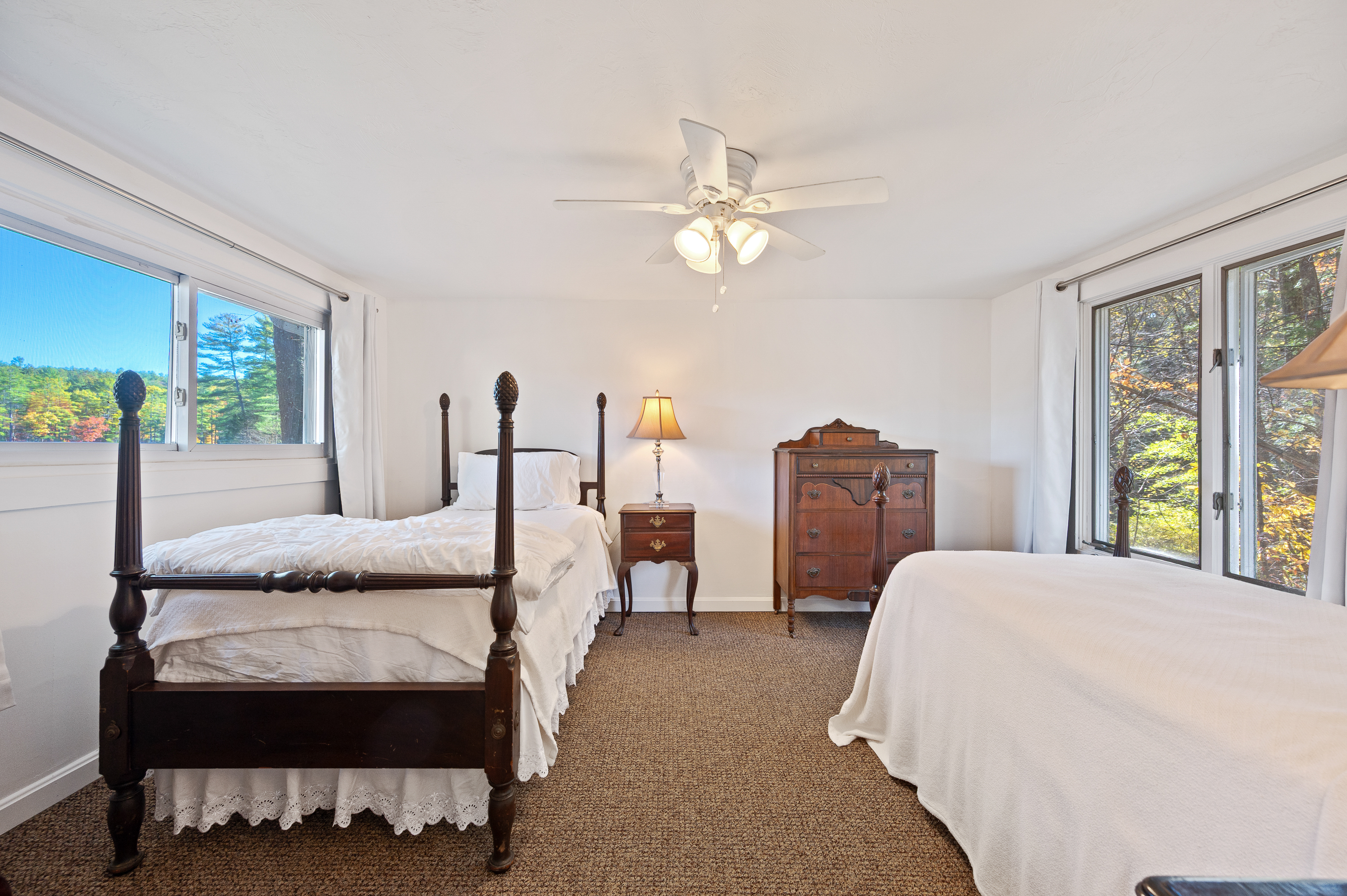 Bright bedroom with two beds, ceiling fan, and classic wooden furniture.