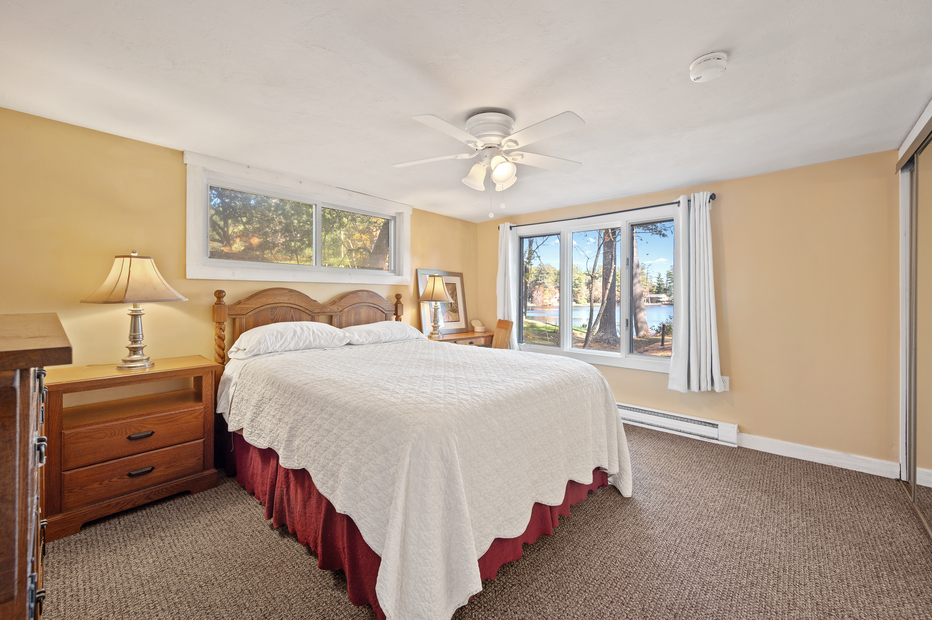 Cozy bedroom with large windows and a ceiling fan.