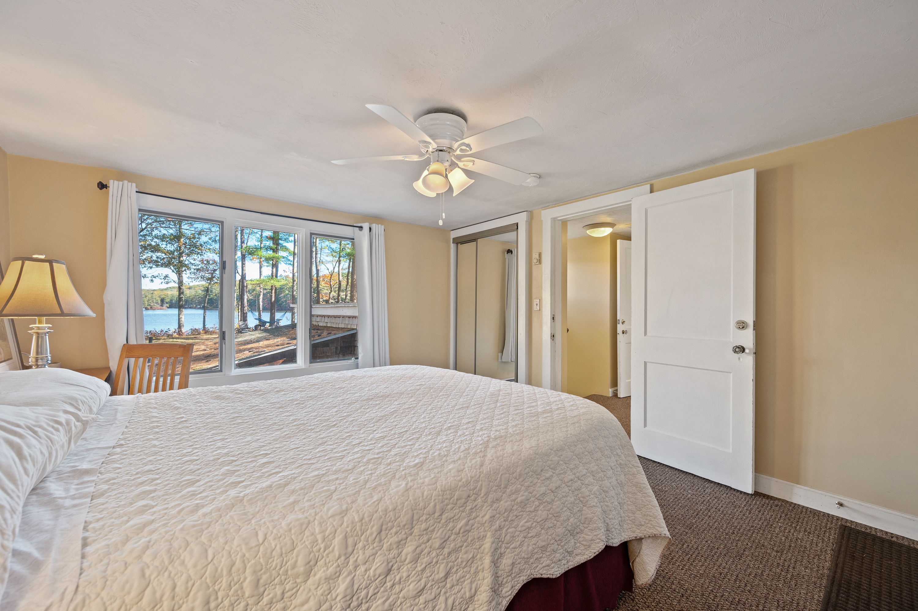 Cozy bedroom with large windows and ceiling fan.