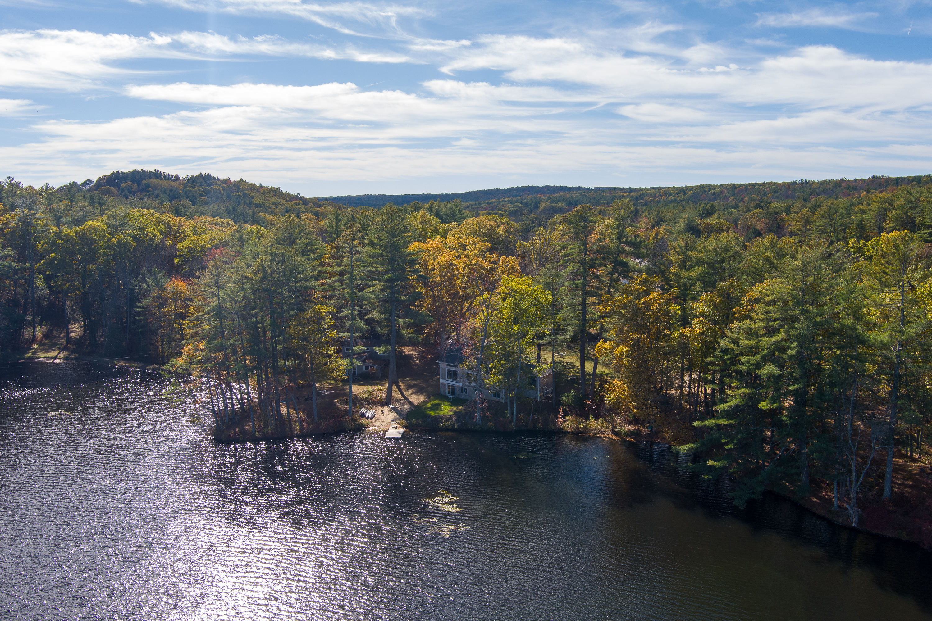 Scenic lake surrounded by autumn trees under a partly cloudy sky.