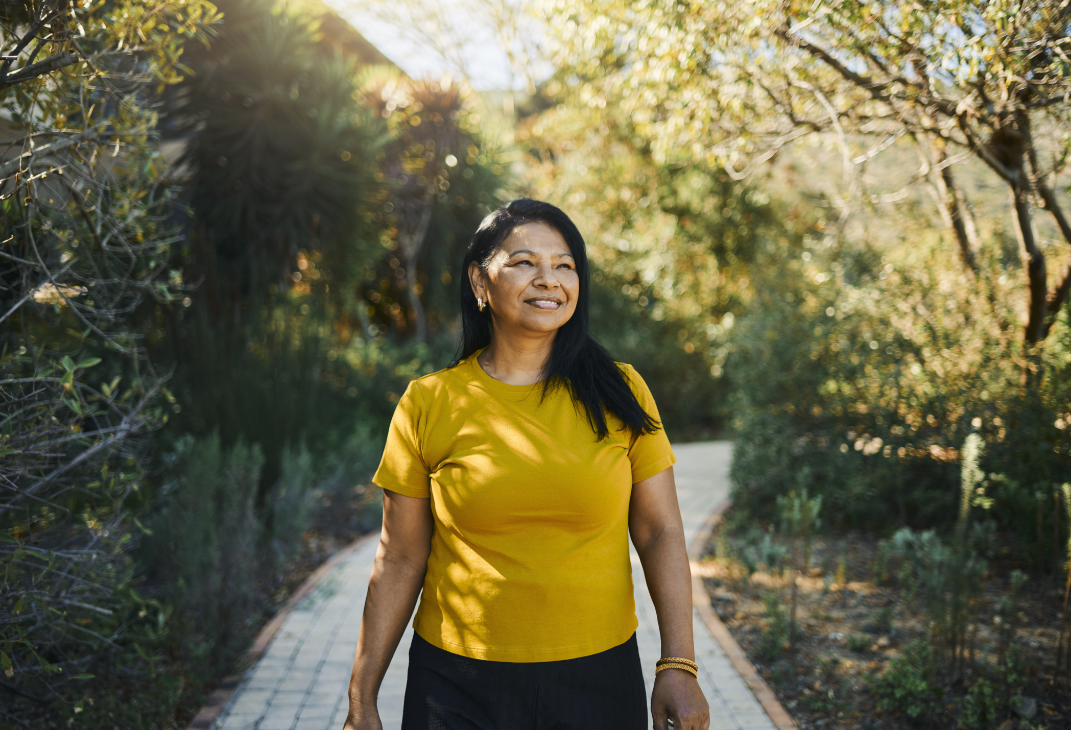 A joyful woman walking outdoors on a sunny day.