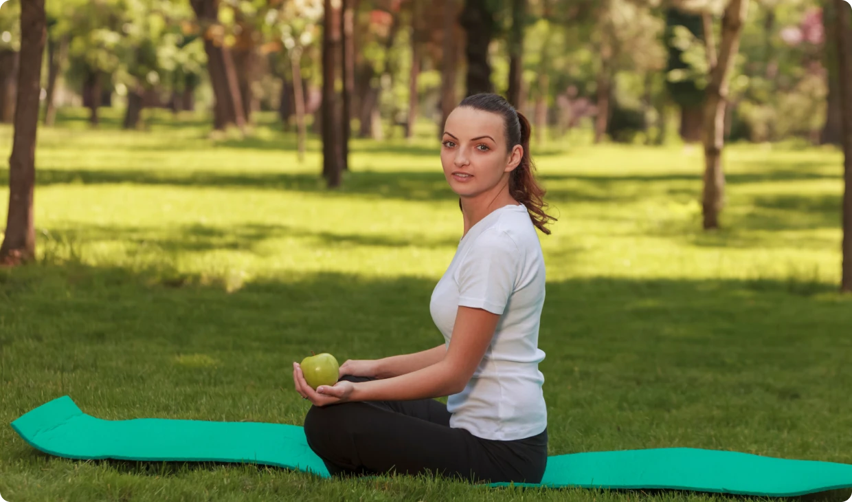 Woman sitting on yoga mat outdoors