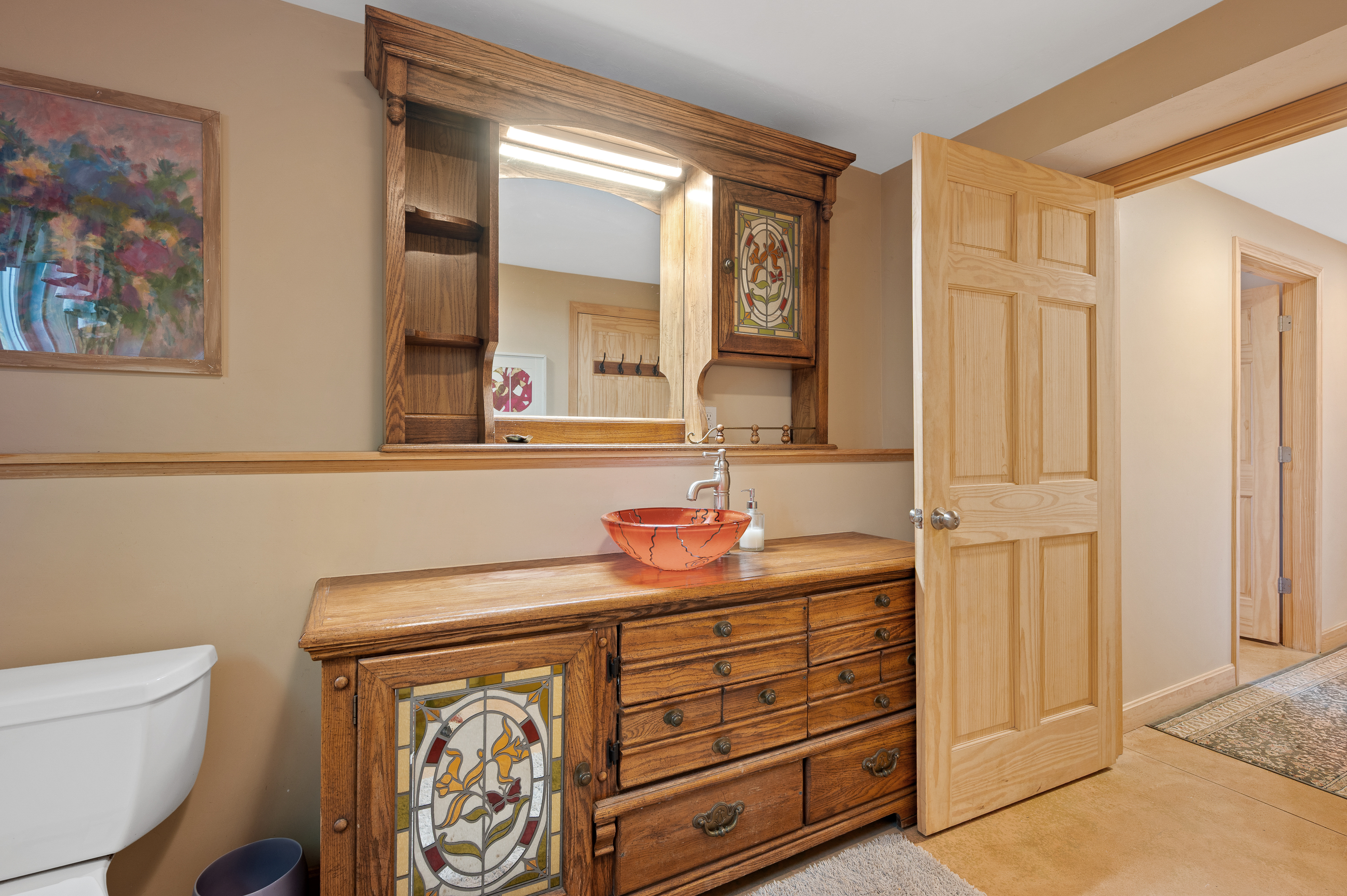 Rustic wooden dresser with decorative clock and bowl in cozy room.