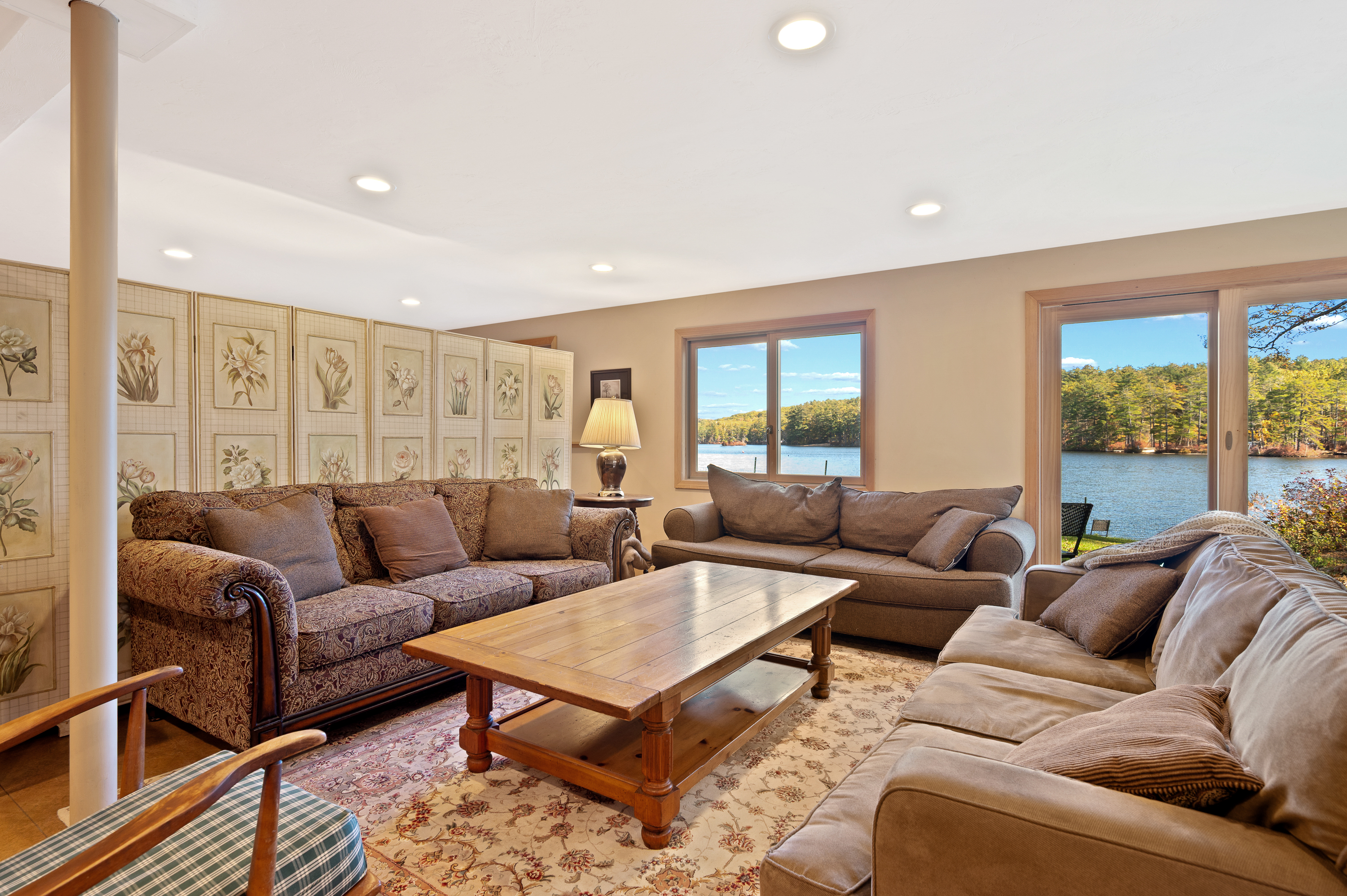 Cozy living room with brown sofas and a wooden coffee table near large windows.